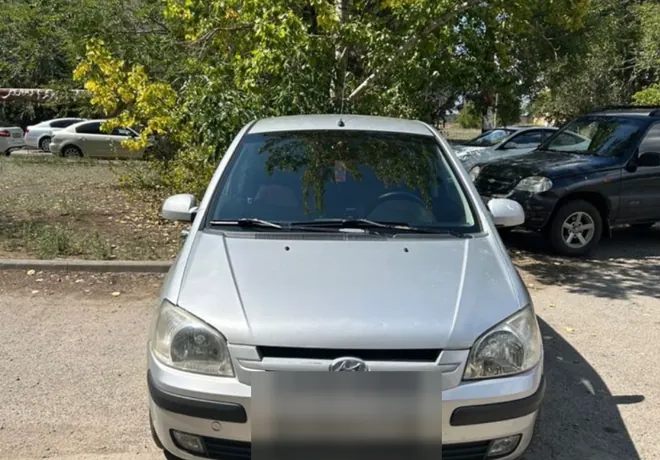 Серебристый Hyundai Getz показан спереди на обычной стоянке.
