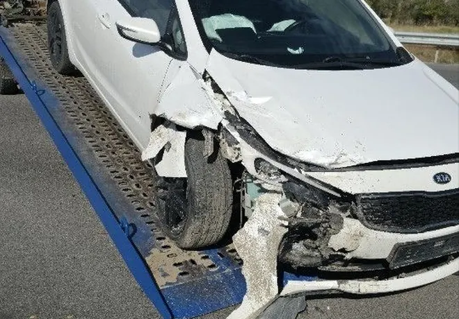 Белый Kia Rio с разрушенной передней угловой частью; на фото автомобиль уже находится на платформе.