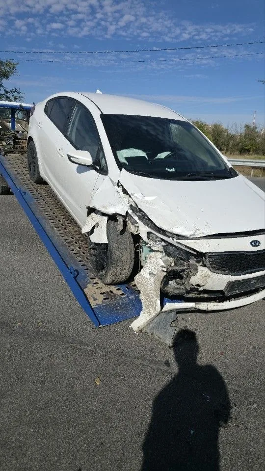 Белый Kia Rio с разрушенной передней угловой частью; на фото автомобиль уже находится на платформе.