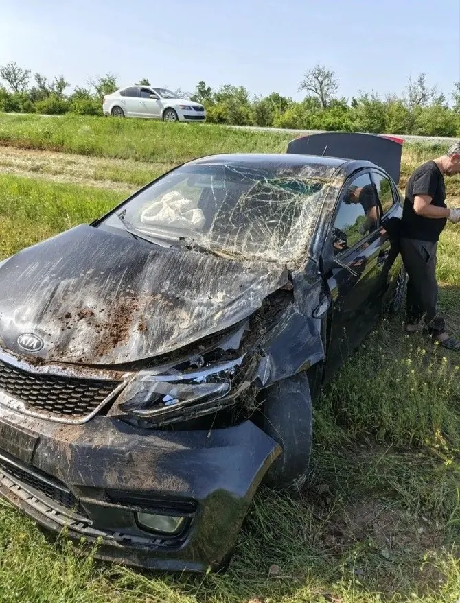 Тёмный Kia Rio с серьёзными повреждениями спереди, разбитым лобовым стеклом и видимыми следами удара по кузову.