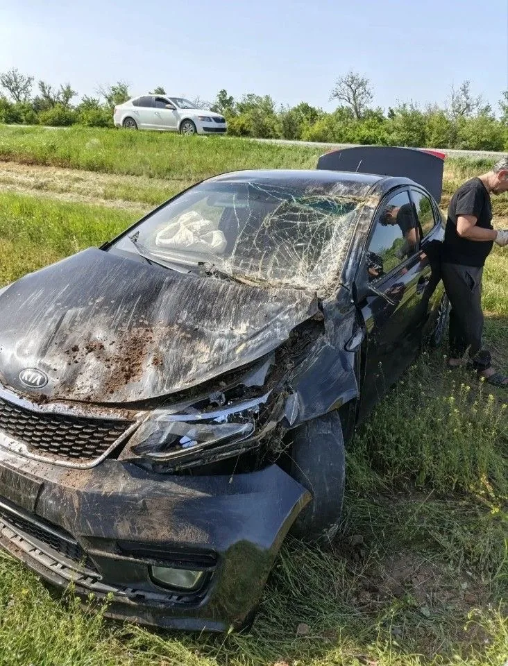 Тёмный Kia Rio с серьёзными повреждениями спереди, разбитым лобовым стеклом и видимыми следами удара по кузову.