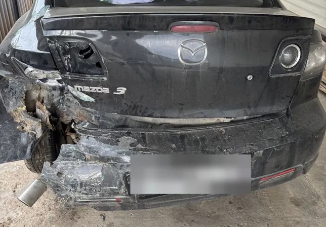 Чёрная Mazda 3: деформация крышки багажника, заднего бампера и левого крыла.