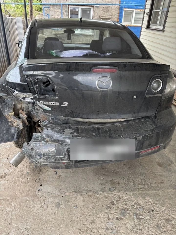 Чёрная Mazda 3: деформация крышки багажника, заднего бампера и левого крыла.